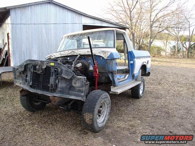 Ford truck body with front end removed, blue and white cab, jack under chassis