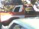 1978 Ford Bronco - A red and white 1978 Ford Bronco with a roof rack is partially visible, parked behind another vehicle.