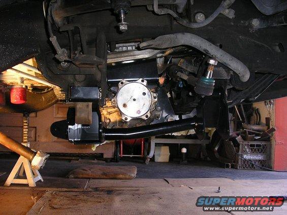 Close-up of vehicle's front suspension and differential assembly, showing steering linkage and brake components