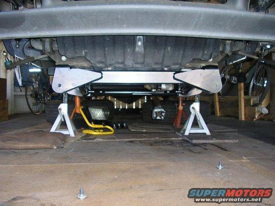 Undercarriage of a vehicle on jack stands, showing suspension components and tires