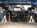 1979 Chevrolet C/K Pickup - Vehicle underbody with transmission and exhaust system components, raised on jack stands for maintenance.