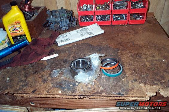 Workbench with Pennzoil oil, carburetor, red bins of hardware, cloth, and wheel bearings