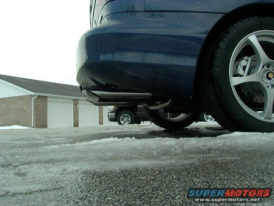Blue car rear bumper and wheel with exhaust pipe visible