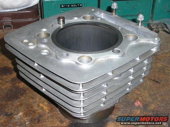 Aluminum engine cylinder block with cooling fins, resting on a metal stand