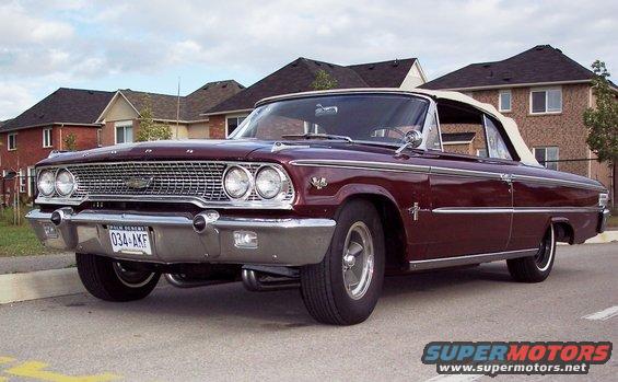 Maroon 1963 Ford Galaxie convertible with a tan top, parked on a street. The front grille and headlights are visible