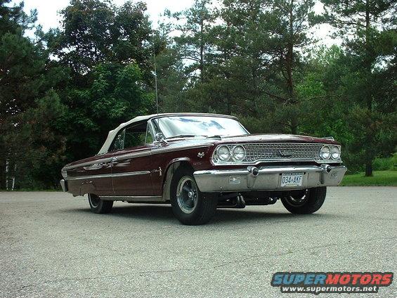 Maroon 1963 Ford Galaxie convertible parked outside with trees in background. License plate is 034-AKF