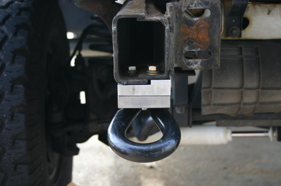 Close-up of a black tow hook mounted to a vehicle's frame, with a tire visible on the left