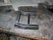 1985 Ford Crown Victoria LTD - A custom-made metal component rests on a worn wooden surface, possibly awaiting installation.