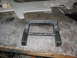 1985 Ford Crown Victoria LTD - A metal frame part sits on a workbench covered in debris and tools.