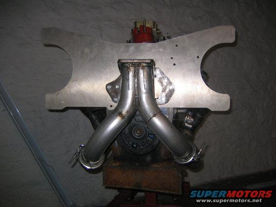 Engine with custom exhaust pipes and a red carburetor, mounted on a stand