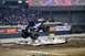 1976 Ford F-150 - A monster truck soars through the air over a pile of crushed cars during an event at an arena.