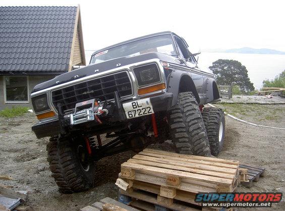 Ford truck with big tires, winch on front bumper, parked on wooden pallets