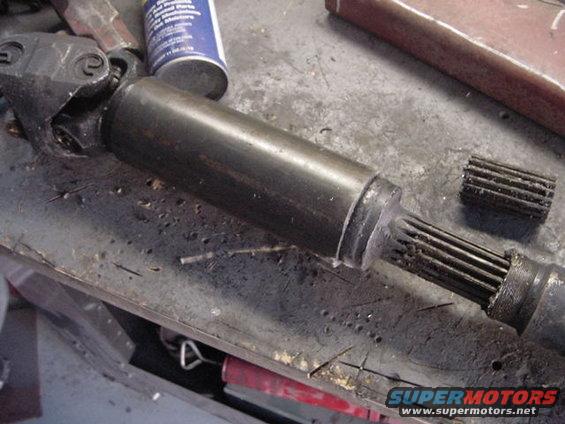Driveshaft with splines visible, sitting on a workbench next to a can