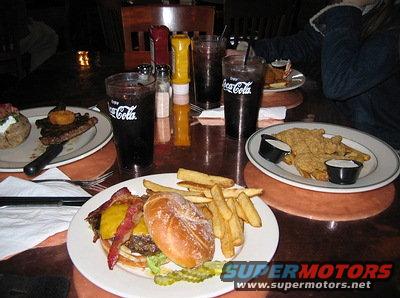 Table with burgers, fries, steak, baked potato, and Coca-Cola drinks