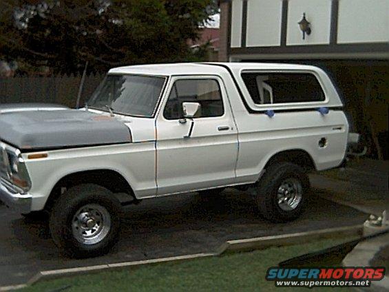 White 1978 Ford Bronco with a grey hood parked outside a garage