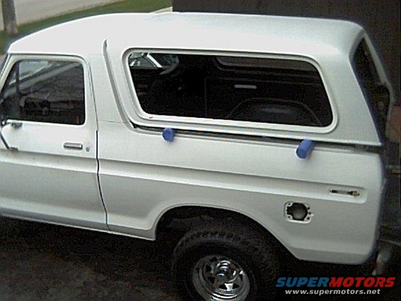 White 1978 Ford Bronco with camper shell, side view, showing dented fuel door area