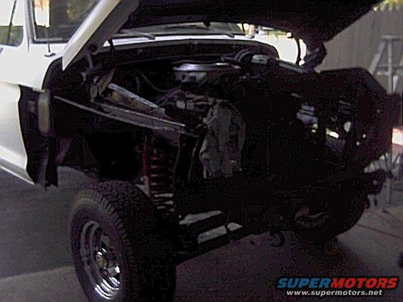 White 1978 Ford Bronco with hood open, showing engine and front suspension. Chrome wheels visible