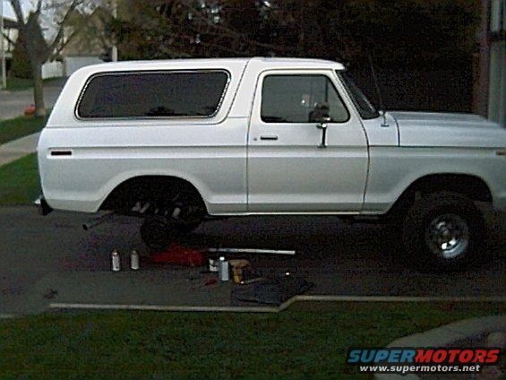 Side view of a white 1978 Ford Bronco with rear wheel removed