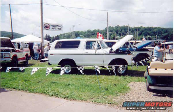 1978 Ford Bronco parked at an outdoor event, hood open. Another vehicle is partially visible to the left