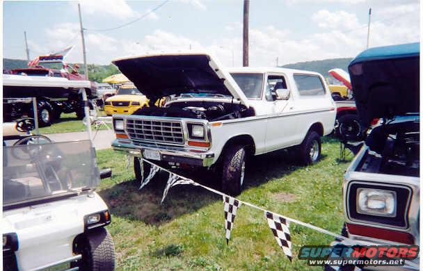 White 1978 Ford Bronco with hood open, parked on grass with other vehicles around