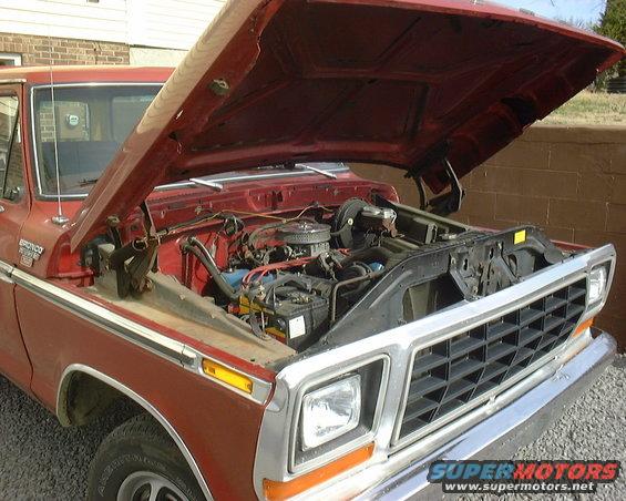 red pickup truck, hood open, showing engine bay. Grille and headlights visible