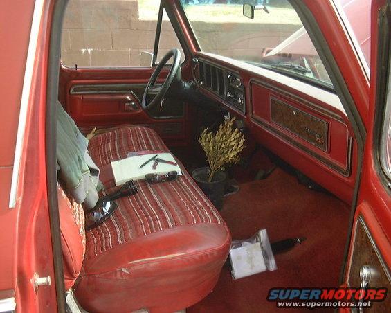 1978 Ford Bronco interior with red striped seats, wood grain trim, and a potted plant