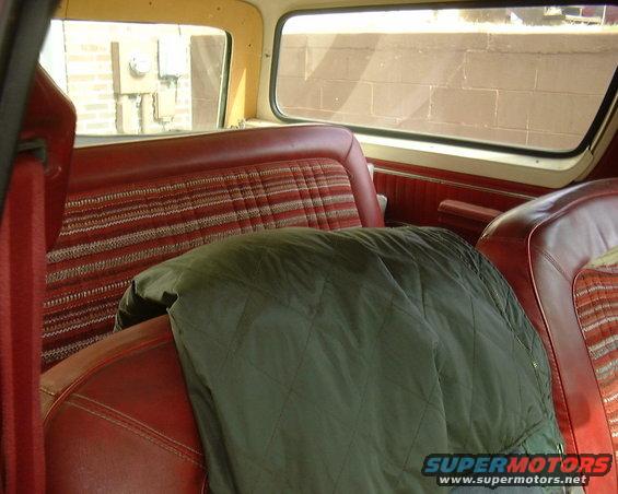 1978 Ford Bronco interior showing red seats with plaid inserts and a green blanket on the passenger seat