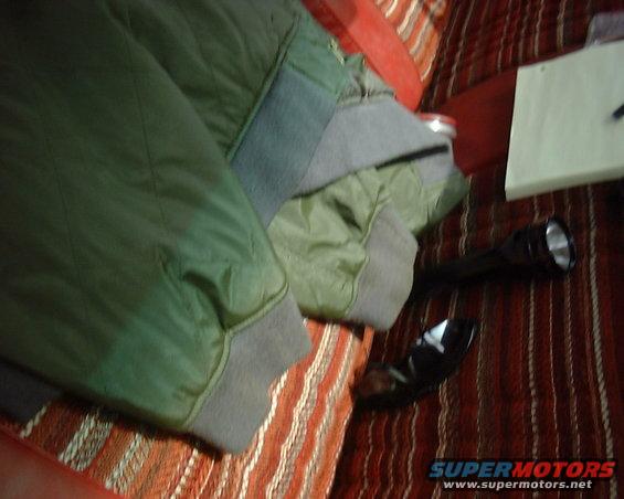 green jacket and flashlight on a striped surface