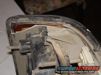 Close-up of a dusty vehicle headlight assembly with mounting hardware visible
