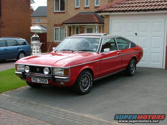 Red coupe with black roof parked in driveway. License plate PUL 295R