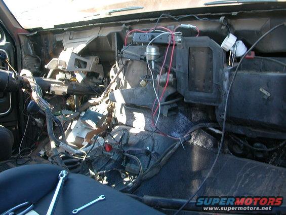 Disassembled dashboard interior with exposed wiring and tools on seat