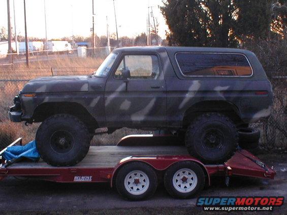 Side view of a 1979 Ford Bronco with camouflage paint on a trailer
