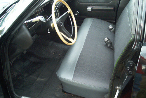 Interior view of a car with a bench seat, steering wheel, and dashboard