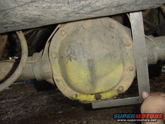 Rear differential housing with a ruler measuring its diameter. The housing is yellow and rusty