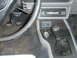 1986 Ford Mustang - Close-up of the driver's side interior, pedals, a manual gear shifter, and an aftermarket radio.