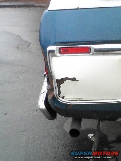 1978 Ford Bronco rear corner with rust damage on the tailgate and a chrome bumper