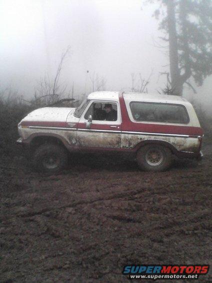 White and red Ford Bronco in mud, side view