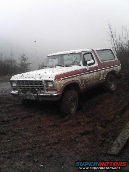 1978 Ford Bronco driving through mud with red and white paint