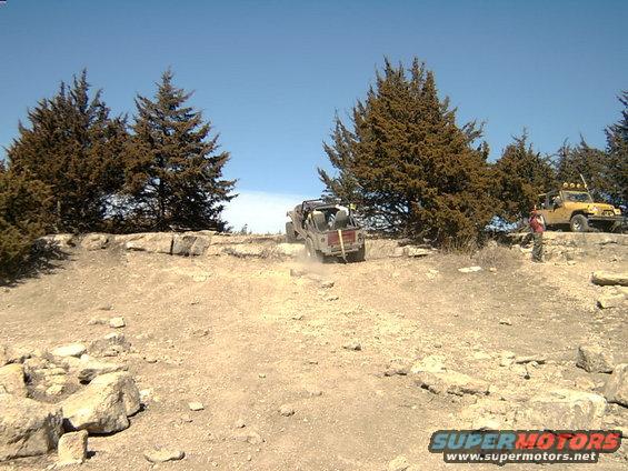1998 Jeep TJ climbing a rocky hill, another Jeep parked on the ridge above