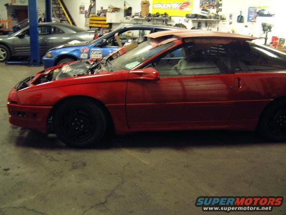 red sports car with hood open, another blue car and gray car behind it in a garage