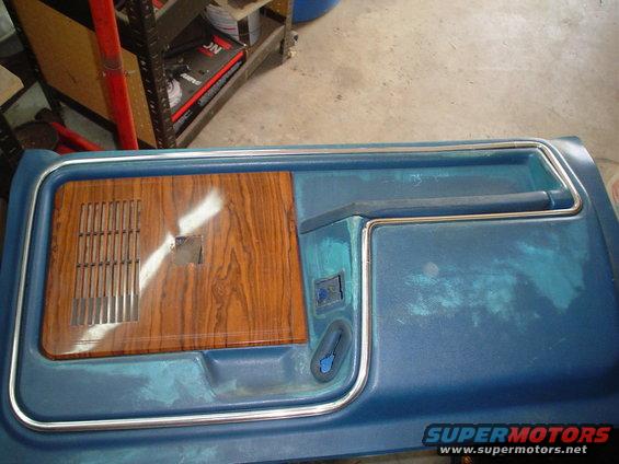 blue car door panel with wood grain insert and chrome trim