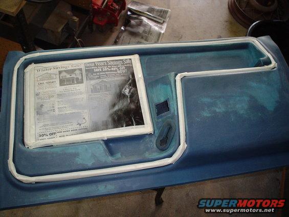 Blue door panel with white trim and a folded newspaper inside. A black handle is visible