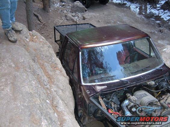 Brown Ford Bronco off-roading, hood open, stuck between rocks