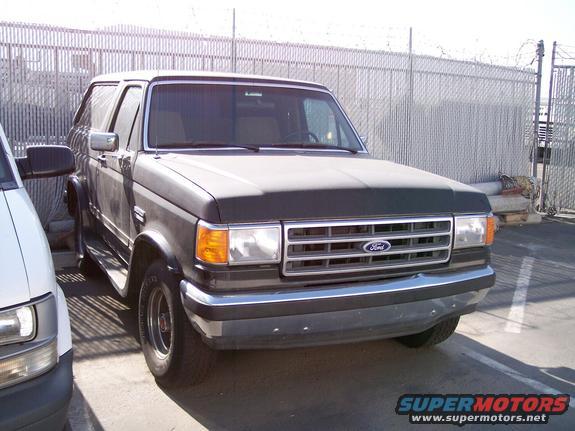 Dark gray Ford Bronco parked next to a white van, front 3/4 view