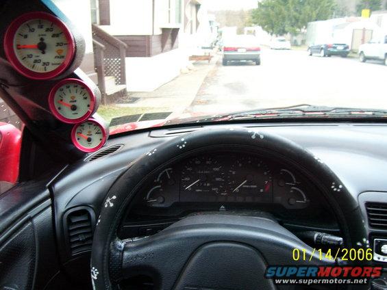1994 Ford Probe interior showing steering wheel, dashboard gauges, and aftermarket gauges on the A-pillar