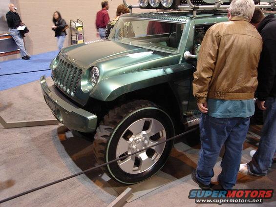 Green Jeep Wrangler concept vehicle with roof rack and large tires, viewed from the front three-quarter angle at an auto show