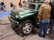 2000 Ford Crown Victoria - A green Jeep Wrangler concept vehicle is displayed at an auto show, with onlookers observing.