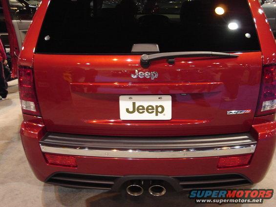Rear view of a red Jeep Grand Cherokee SRT8 with dual exhaust pipes and a license plate frame that says Jeep