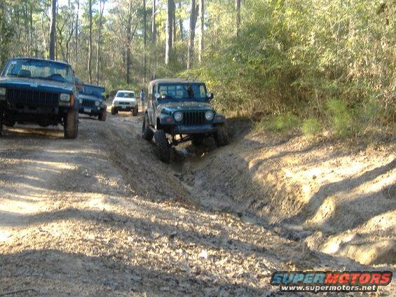 Green Jeep Wrangler navigating a muddy trail, 1997