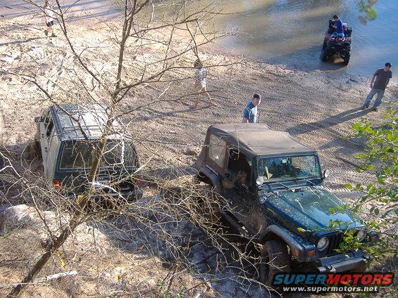 1999 Jeep Wrangler in mud near water, another Jeep stuck in background, ATV in water